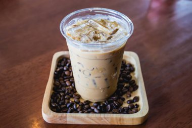 Soğuk kahve içecek frappe veya frappuccino içinde ahşap masa üzerinde kahve çekirdeği ile ahşap tepsi