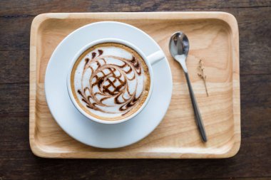 Güzel beyaz kahve sanat desen ahşap tepsi whute kaşık masada. Odağı seçin