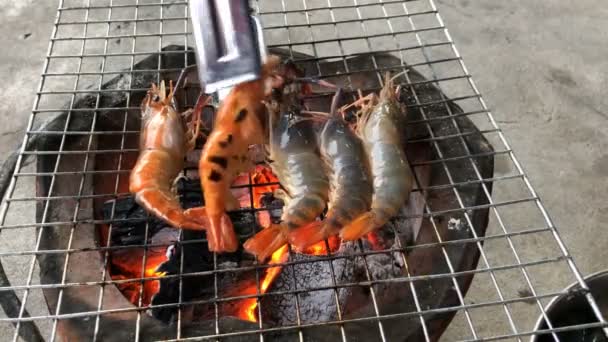 伝統的な炭火とフリップフリップハンドで燃えるグリルで焼いた新鮮なエビ — ストック動画
