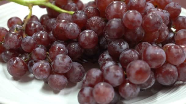 Bunches Uvas Vermelhas Com Gotas Água Placa Branca Está Girando — Vídeo de Stock