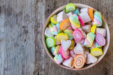 Ahşap arka planda bir kasede marşmelov pastası ve jelibon şekeri. Alan arkaplanı ve dokuyu kopyala