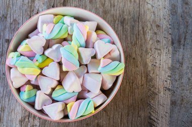 Çok renkli şekerlemeler ve ahşap arka planda bir kasede kalp. Alan arkaplanı ve dokuyu kopyala