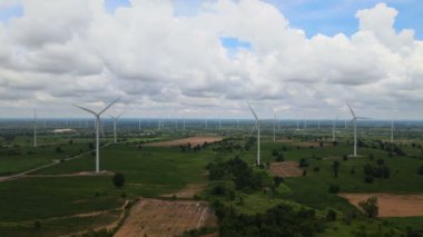 Tayland 'da arka plan olarak dağlarla ve gökyüzüyle çayırlarda elektrik üretmek için birçok rüzgar türbini.