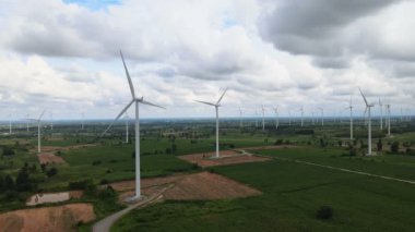 Tayland 'da arka plan olarak dağlarla ve gökyüzüyle çayırlarda elektrik üretmek için birçok rüzgar türbini.