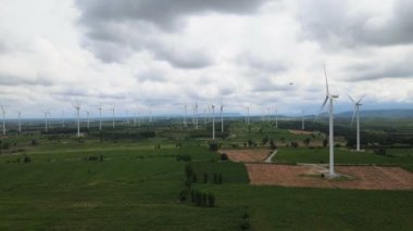 Tayland 'da arka plan olarak dağlarla ve gökyüzüyle çayırlarda elektrik üretmek için birçok rüzgar türbini.