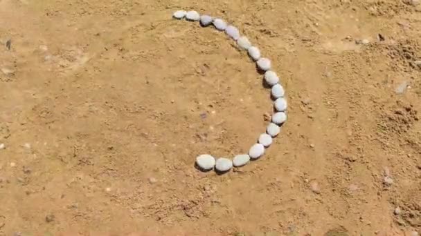 Pequeños guijarros corren en fila a lo largo de la arena, convirtiéndose en el sol en un movimiento de parada, que se convierte en un corazón. La siguiente es la inscripción Crimea. El concepto de actividades al aire libre, viajes . — Vídeo de stock