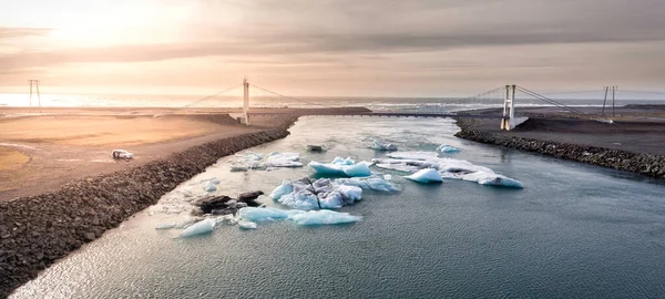 アイスランドの氷河のラグーンに散在する氷の塊と画像を横断する橋 — ストック写真