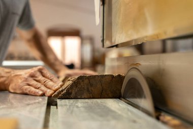 Marangoz kulak tıkacı takan bir makineyle odun kesiyor. Seçici odak