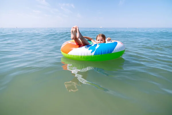 girl lying on an colorful inflatable mattress whee enjoying herself in the middle of the blue sea in summer holidays