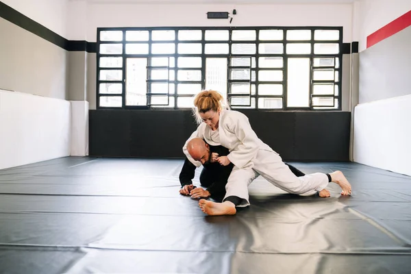 Judo ya da kimonolu karate gibi dövüş sanatları eğitiminin üç partneri spor minderinde pratik yapıyor. Hepsi de kovid 19 koronavirüs salgınından dolayı maske takıyor.