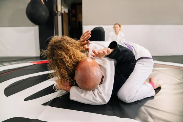 two female and male judo martial arts fighters practicing new techniques on a gym mat
