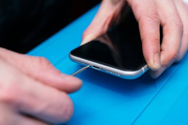 Uzman, akıllı telefon parçalarını mavi bir mindere ayırır.