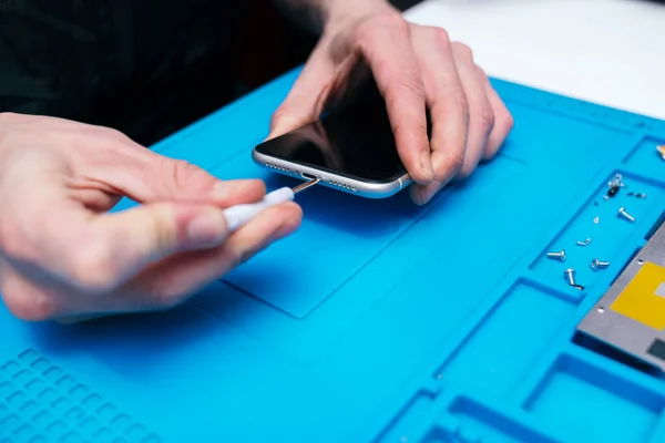 Close-up of technician\'s hands repairing a phone