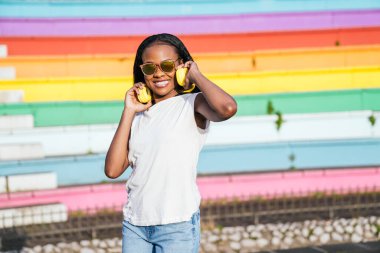 Neşeli bayan, arka planda gökkuşağı duvarı olan müzikten hoşlanıyor..