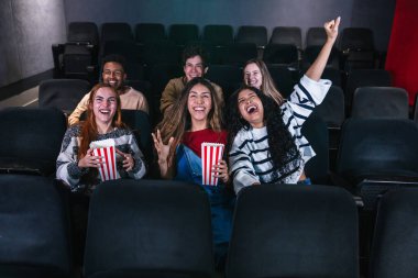 Bir spor müsabakasında zaferi izleyen ve sevinçten havalara uçan bir grup genç, kollarını kaldırarak kutlama yapıyorlar.