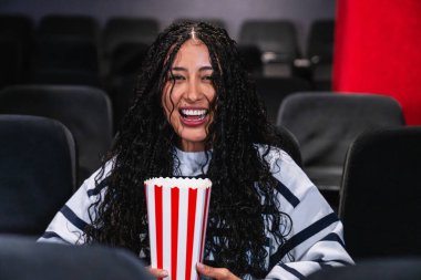 Sinema salonunda elinde patlamış mısırla gülen mutlu bir müşteri.