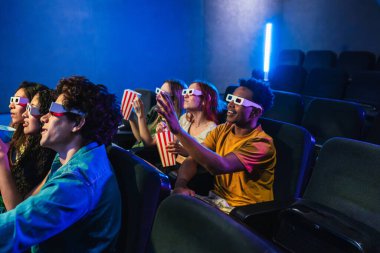 Gençler 3D gözlük takıyor, sinemada film izlerken patlamış mısır yiyor, birlikte kahkaha ve heyecan paylaşıyorlar.