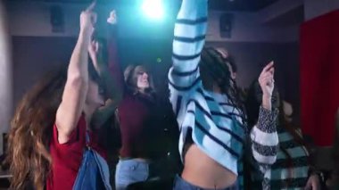 Loş ışıklı barda dans eden gençler, bulaşıcı enerji ve yavaş çekimde neşeli hareketlerle spontane kutlamaların tadını çıkarıyorlar.