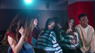 Bir barda dans eden çok ırklı arkadaşlar, yavaş çekimde eşsiz ve eğlenceli bir deneyimin tadını çıkarıyorlar.