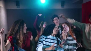 Bir barda birlikte dans eden çok ırklı bir grup, yavaş çekimde arkadaşlığın spontane kutlaması sırasında enerjiyle paylaşıyorlar.