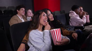 Lezbiyen çift özel sinema anlarını paylaşıyor, sinemadan ve patlamış mısırdan keyif alıyor yumuşak, yavaş çekimde gizli bir bağlantı ve mutluluk sahnesinde.