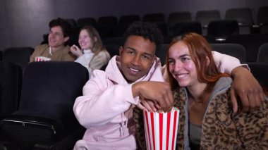 Sinemada patlamış mısırları paylaşan genç bir çift romantik bir yavaş çekim sahnesine çekiliyor.