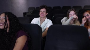 Genç arkadaşlar sinemada komedi filminin keyfini çıkarıyorlar, senkronize ağır çekimde gerçek kahkahaları paylaşıyorlar, kolektif eğlencenin neşeli anlarını yakalıyorlar.