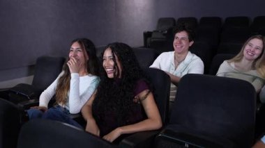 Genç arkadaşlar, karanlık sinema salonunda film izlerken kahkaha ve keyif paylaşıyorlar. Yavaş çekimde gerçek bağlantıyı ve mutluluğu yakalıyorlar.