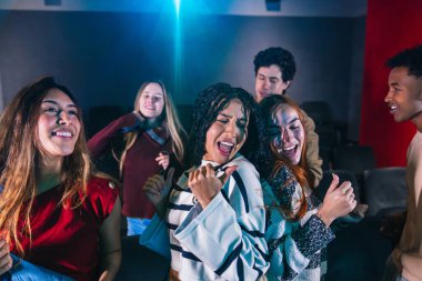 Bir grup arkadaş bir müzikholde eğleniyor ve şarkı söylüyor, eğleniyor ve dans ediyorlar.