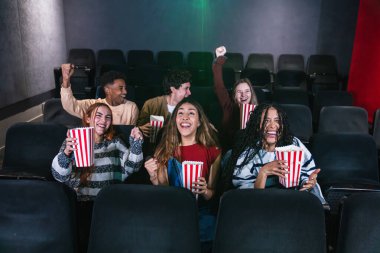 Bir spor müsabakasında zaferi izleyen ve sevinçten havalara uçan bir grup genç, kollarını kaldırarak kutlama yapıyorlar.