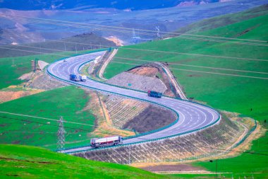 Manzara. Yeşil dağdaki öküz sürüsü, arka plan olarak otoyol ve güç kuleleri, Tibet Platosu, Çin 'de oluşturuldu.