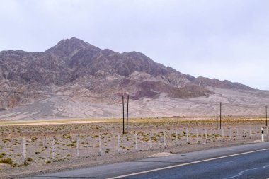 Uçsuz bucaksız kurak arazide Çin 'in kuzeybatısındaki Qinghai eyaletinde tek bir kişi bile olmadan bir asfalt yol mekiği geçiyor..