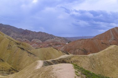 Gökkuşağı Dağı 'nın muhteşem manzarası ve gün batımında mavi gökyüzü arkaplanı. Zhangye Danxia National Geopark, Gansu, Çin. Renkli manzara, gökkuşağı tepeleri, sıra dışı renkli kayalar, kumtaşı erozyonu.