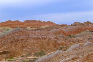 Gökkuşağı Dağı 'nın muhteşem manzarası ve gün batımında mavi gökyüzü arkaplanı. Zhangye Danxia National Geopark, Gansu, Çin. Renkli manzara, gökkuşağı tepeleri, sıra dışı renkli kayalar, kumtaşı erozyonu.