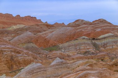 Gökkuşağı Dağı 'nın muhteşem manzarası ve gün batımında mavi gökyüzü arkaplanı. Zhangye Danxia National Geopark, Gansu, Çin. Renkli manzara, gökkuşağı tepeleri, sıra dışı renkli kayalar, kumtaşı erozyonu.