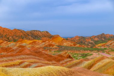 Gökkuşağı Dağı 'nın muhteşem manzarası ve gün batımında mavi gökyüzü arkaplanı. Zhangye Danxia National Geopark, Gansu, Çin. Renkli manzara, gökkuşağı tepeleri, sıra dışı renkli kayalar, kumtaşı erozyonu.