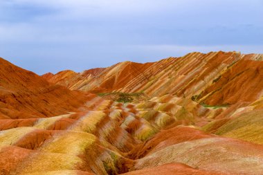 Gökkuşağı Dağı 'nın muhteşem manzarası ve gün batımında mavi gökyüzü arkaplanı. Zhangye Danxia National Geopark, Gansu, Çin. Renkli manzara, gökkuşağı tepeleri, sıra dışı renkli kayalar, kumtaşı erozyonu.