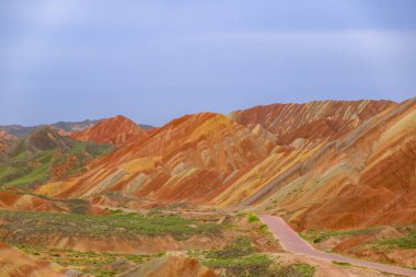 Gökkuşağı Dağı 'nın muhteşem manzarası ve gün batımında mavi gökyüzü arkaplanı. Zhangye Danxia National Geopark, Gansu, Çin. Renkli manzara, gökkuşağı tepeleri, sıra dışı renkli kayalar, kumtaşı erozyonu.