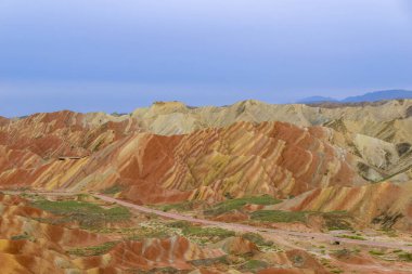 Gökkuşağı Dağı 'nın muhteşem manzarası ve gün batımında mavi gökyüzü arkaplanı. Zhangye Danxia National Geopark, Gansu, Çin. Renkli manzara, gökkuşağı tepeleri, sıra dışı renkli kayalar, kumtaşı erozyonu.