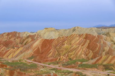 Gökkuşağı Dağı 'nın muhteşem manzarası ve gün batımında mavi gökyüzü arkaplanı. Zhangye Danxia National Geopark, Gansu, Çin. Renkli manzara, gökkuşağı tepeleri, sıra dışı renkli kayalar, kumtaşı erozyonu.