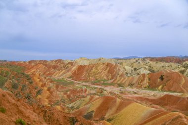 Gökkuşağı Dağı 'nın muhteşem manzarası ve gün batımında mavi gökyüzü arkaplanı. Zhangye Danxia National Geopark, Gansu, Çin. Renkli manzara, gökkuşağı tepeleri, sıra dışı renkli kayalar, kumtaşı erozyonu.
