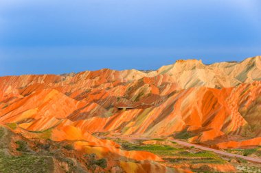 Gökkuşağı Dağı 'nın muhteşem manzarası ve gün batımında mavi gökyüzü arkaplanı. Zhangye Danxia National Geopark, Gansu, Çin. Renkli manzara, gökkuşağı tepeleri, sıra dışı renkli kayalar, kumtaşı erozyonu.