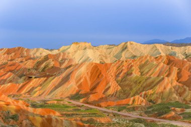 Gökkuşağı Dağı 'nın muhteşem manzarası ve gün batımında mavi gökyüzü arkaplanı. Zhangye Danxia National Geopark, Gansu, Çin. Renkli manzara, gökkuşağı tepeleri, sıra dışı renkli kayalar, kumtaşı erozyonu.