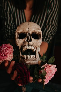 Elinde gül çiçekleri olan bir kafatası. 