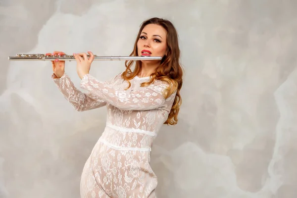 Woman in an artist\'s costume play flute on white background. Flute in hand. Stylish girl with musical instrument (flute). Photo for magazine cover, website with space for an inscription or logo