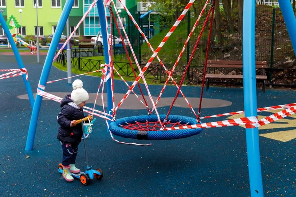 Barn på stängd lekplats. Sorgsen upprörd flicka på skoter på stängd uteplats — Stockfoto