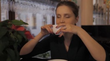 Akşamları siyah gömlekli Slav kız kahve ve telefonla masaya oturuyor ve duygularını gösteriyor. Kadın bekler, kupadan çay içer ve gülümser. Genç bir kadının (yüzü) yakın plan