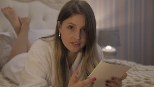 Dziewczyna Słowiańskim Wyglądzie Białym Płaszczu Leży Łóżku Hotelu Czyta Menu — Wideo stockowe