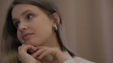 Beyaz gömlekli Slav aktris kız duygularını gösteriyor. Kadın üzgün görünüyor, saçlarını düzleştiriyor ve etrafına bakıyor. Genç bayanın (yüzü) yakın plan