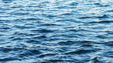 Su yüzeyindeki dalgalar. Dalga deseni. Yüzeyin temiz ya da deniz suyunun görüntüsü. Deniz dalgaları. Deniz ya da okyanus dalgalarının arka planı. Su yüzeyi duvar kağıdı ya da arka plan konsepti. Gürültülü fotoğraf suyu dalgalandırır